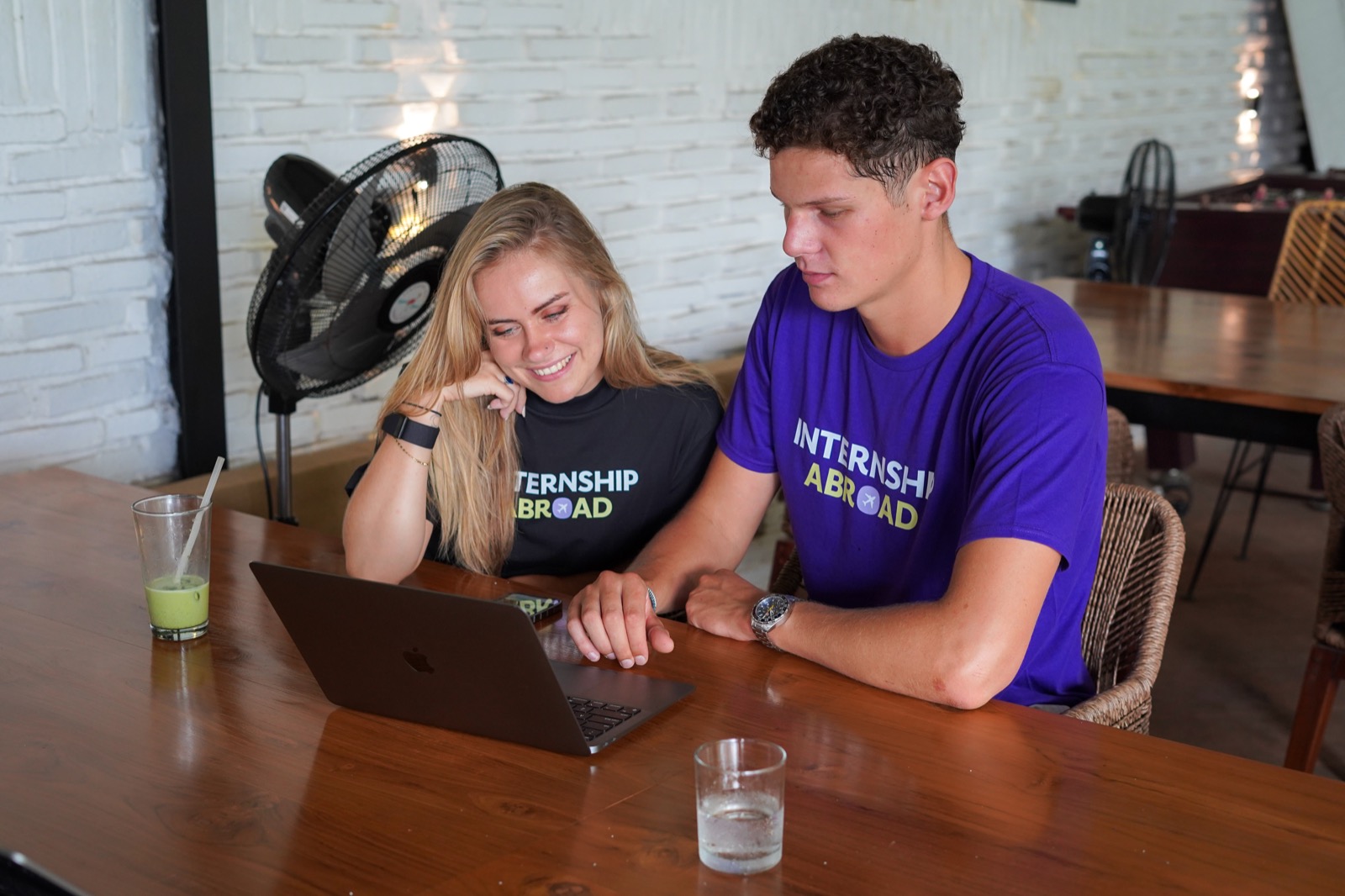 Two Internship Abroad team members working together on a laptop at a cafe in Bali